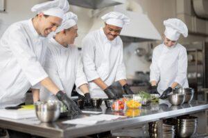 Multiracial team of cooks mixing ingredients for take away food in professional kitchen